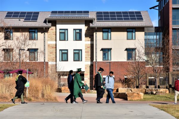 Building with solar panels and graduates walking in front