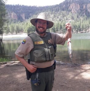 Aaron in a national park ranger uniform with a caught fish.