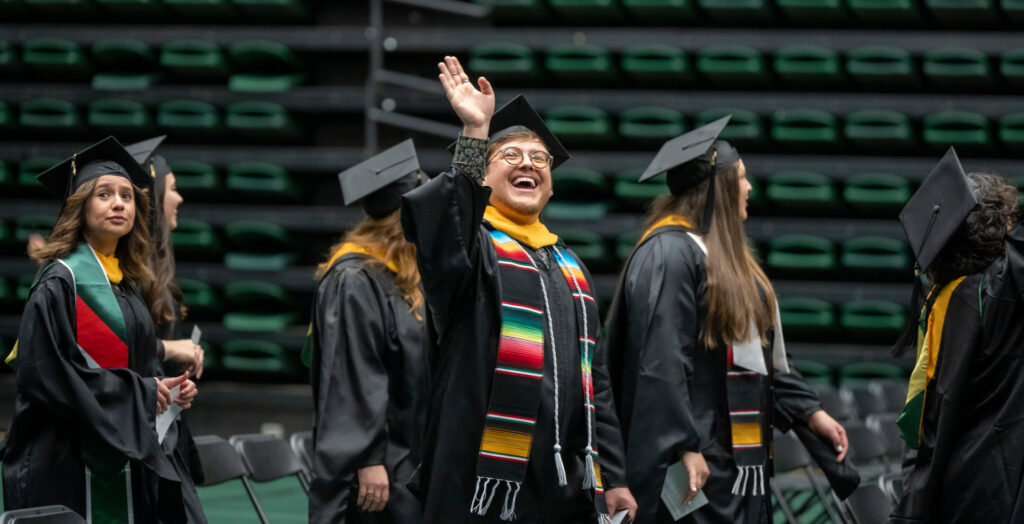person waves to crowd at commencement