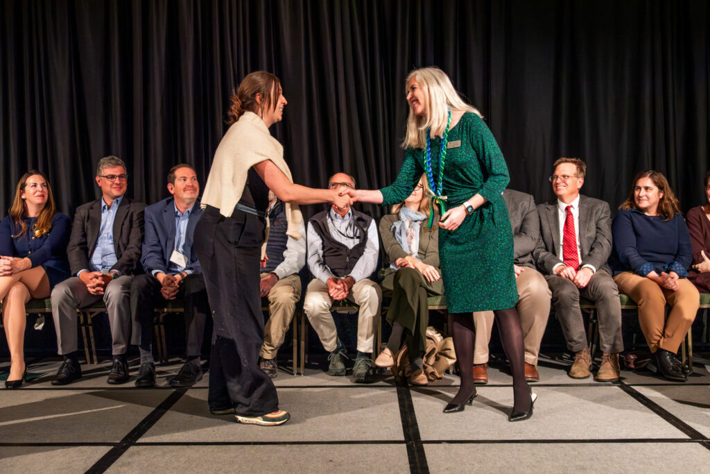 person shakes hand to receive award at the gradshow